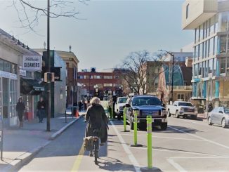 A woman bikes on the two-way protected bike lane on Brattle Street