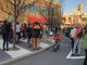 A child bikes up a curbside bike lane as people stand along the border, forming a human barrier protecting the bike lane.