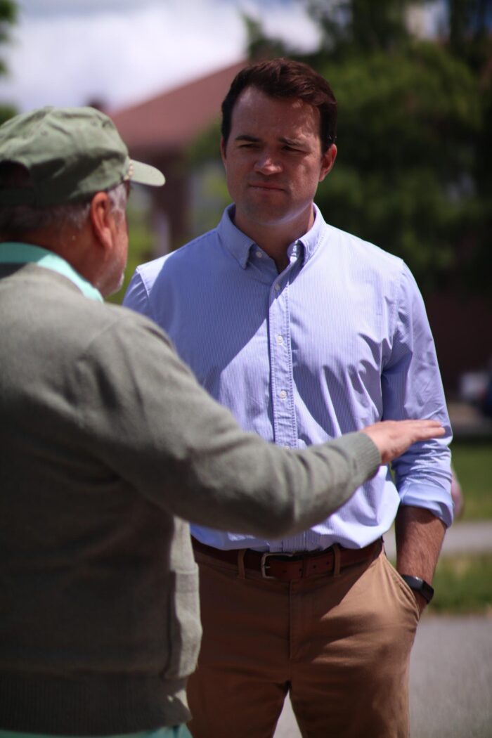 Photo of Ned Melanson speaking to a person wearing a hat. 