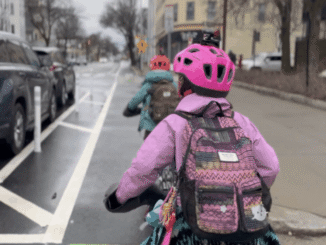 Two children in a bike lane - one in a pink jacket and helmet.