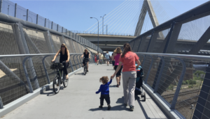 Families using the North Bank Pedestrian Bridge in East Cambridge, on foot and bike.