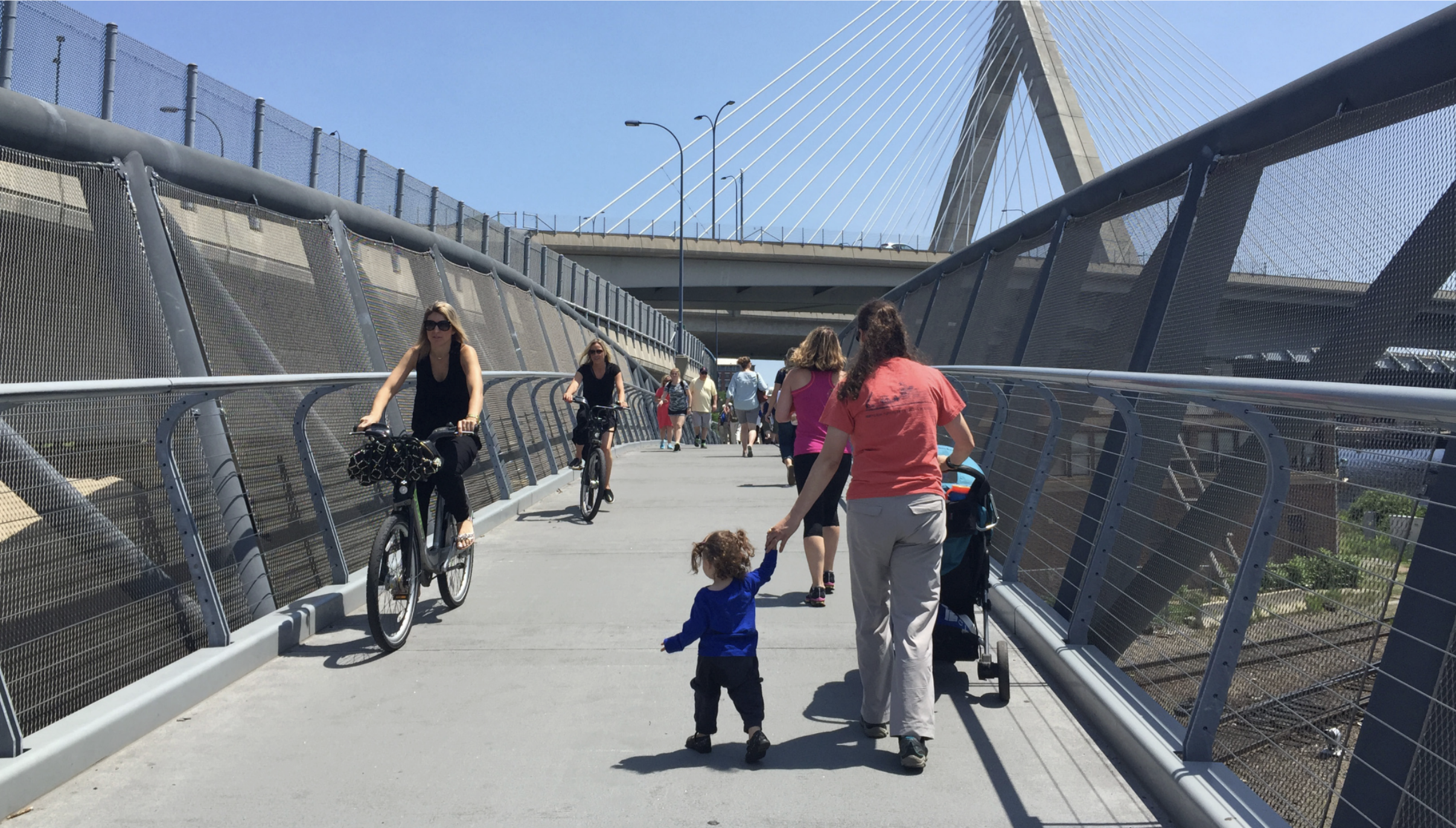 Families using the North Bank Pedestrian Bridge in East Cambridge, on foot and bike.